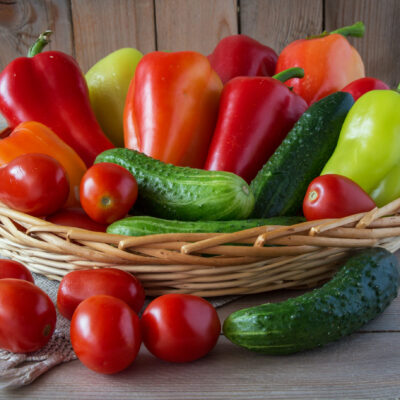 cucumbers,  tomatoes and sweet peppers in a wooden basket